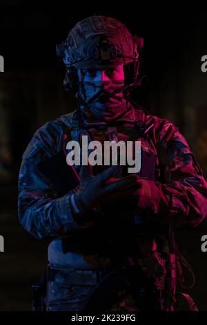 Photo d'un soldat entièrement équipé avec un gilet tactique d'armure noire et des gants debout sur fond noir vue rapprochée de devant. Banque D'Images