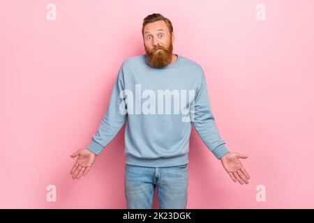 Photo de l'homme beau positif impressionné avec la barbe rouge vêtu pull bleu épaules hausser isolées sur fond de couleur rose Banque D'Images