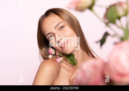 Ressort. Belle jeune fille avec des cheveux blonds brillants tenant la fleur isolée sur fond blanc. Formes et lignes, cosmétiques, beauté naturelle Banque D'Images