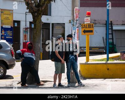 La Paz, Bolivia - September 11 2022: Young Bolivian Friends Wearing Black Masks are Waiting for Public Transportation in the Middle of the Street Stock Photo