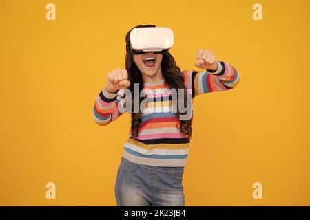 Adolescent stupéfié. Gadgets virtuels pour les enfants, temps libre et étude. Une adolescente utilise des lunettes vr, isolées sur fond jaune. Jeune fille excitée. Banque D'Images