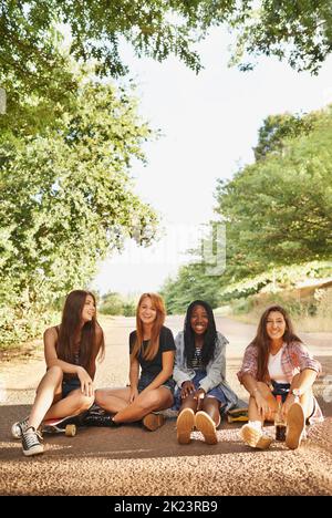 Le rire est une vacances instantanée. Un groupe d'adolescents multiraciaux assis à l'extérieur appréciant chacun d'eux compagnie Banque D'Images