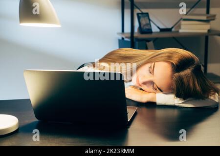 Style de vie de travail. Travailler tard. Travail à distance. Femme d'affaires fatiguée dormant dans un bureau, lampe dans un espace de travail Banque D'Images