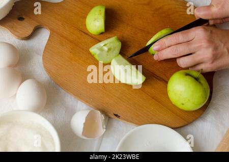 Processus de fabrication de la galette de pomme et de prune maison. Cuisine d'automne traditionnelle de saison. Une femme coupe des pommes sur une planche. Concept de cuisson. Banque D'Images