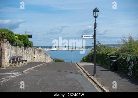 Route le long des falaises à Shanklin sur l'île de Wight, Angleterre avec un panneau à la station de bus, la plage de Sandown et la jetée peuvent être vus dans la distance Banque D'Images