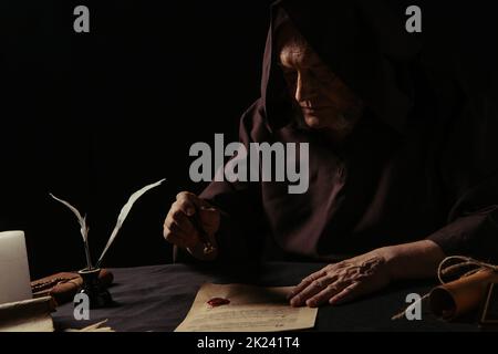 abbé senior en cagoule à capuchon manuscrit estampage avec sceau de cire isolé sur image de stock noir Banque D'Images