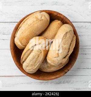 Pain français à grains entiers, pain salé ou pistolet dans un bol sur table en bois. Banque D'Images