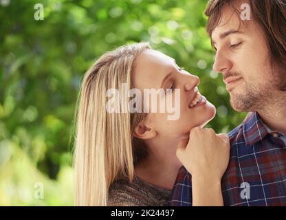 Jeune et plein de passion. Portrait d'un jeune couple souriant qui s'embrasse dans le parc. Banque D'Images