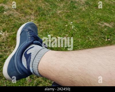 Un pied d'homme avec une chaussure bleue sur fond d'herbe Banque D'Images