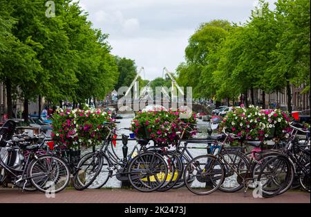 Une photo d'un pont plein de vélos et de fleurs sur un canal à Amsterdam. Banque D'Images