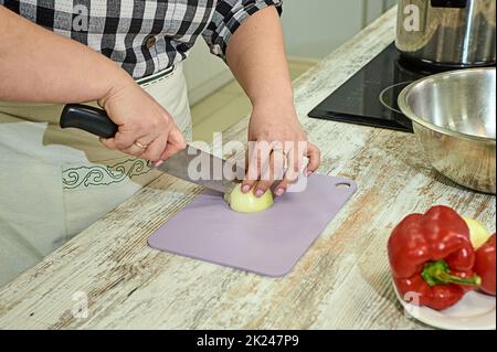 Couper des oignons lors de la cuisson sur une planche. Photo de haute qualité Banque D'Images