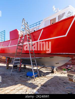 Ancien récipient rouge rouillé en réparation situé sur un réservoir sec et grundy arrimer dans le chantier naval contre le ciel bleu le jour ensoleillé à l'intérieur ancienne usine de construction navale Banque D'Images