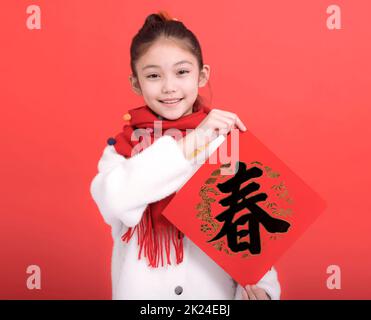 Bonne année chinoise.Fille montrant les couplets du Festival de printemps. texte chinois printemps Banque D'Images