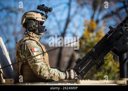 Bucarest, Roumanie - 1 décembre 2021 : un soldat tient une mitrailleuse sur le toit d'un porte-troupes blindé, lors d'un défilé militaire à Buchares Banque D'Images