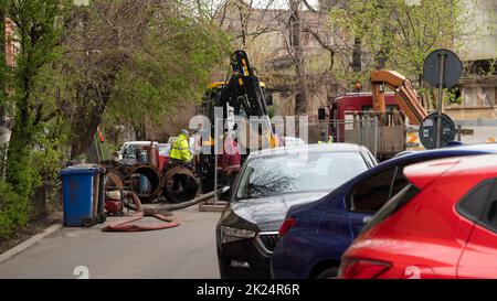 BUCAREST, ROUMANIE - 15 mai 2021: Les travailleurs effectuent des travaux de réparation sur l'égout urbain. Tracteur, trou dans l'asphalte. Banque D'Images