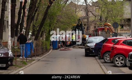 Les travailleurs effectuent des travaux de réparation sur l'égout de la ville. Tracteur, réparation en ville, trou dans l'asphalte. Banque D'Images