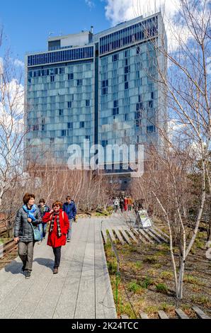 Le High Line Rooftop Park, Chelsea, avec des personnes à pied devant un immeuble de bureaux entouré d'arbres, New York City pendant la journée d'hiver ensoleillée, ver Banque D'Images