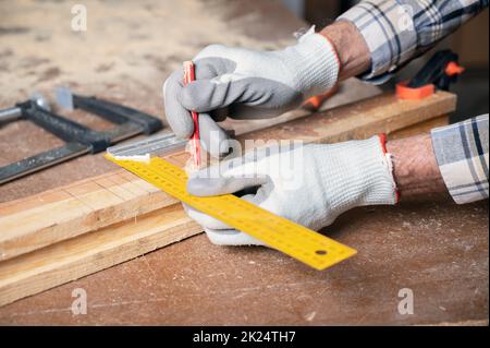 Concept de fabrication de boiseries et de meubles. Le menuisier de l'atelier marque les détails de l'armoire de meubles à l'aide d'une équerre, vue rapprochée. Élevée Banque D'Images