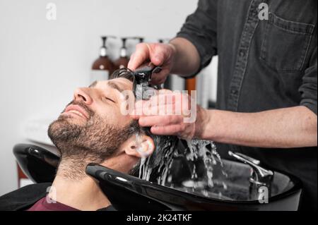 Salon de coiffure. Le coiffeur lave la tête du client dans le salon de coiffure. Photographie de haute qualité Banque D'Images