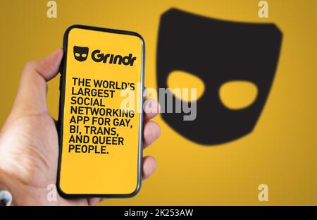 San Francisco, CA, US, mai 2022 : main tenant un téléphone avec l'application mobile Grindr à l'écran. En arrière-plan, le logo Grindr est flou. Grindr est une entrée de données Banque D'Images