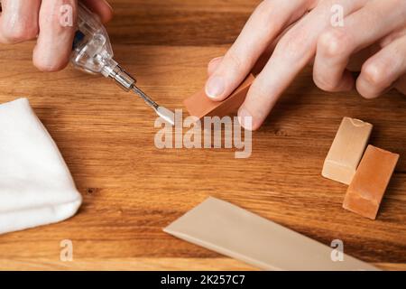 Man heating hard wax for repair cracks, scratches, dents in the wooden floor. Professional repair kit with hard wax sticks. Do-it-yourself laminate or Stock Photo