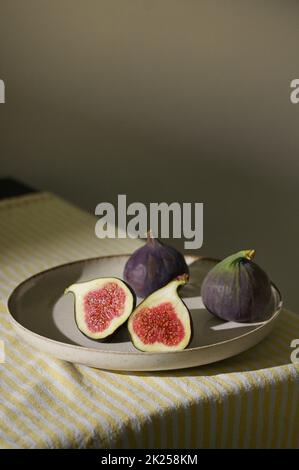 Figues fruits placés sur une petite assiette sur une table avec une nappe et le soleil Banque D'Images