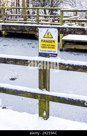 Un panneau près d'un étang gelé dans un parc de Londres avertissement de glace mince et d'eau profonde, nord de Londres, Royaume-Uni Banque D'Images