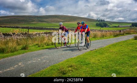 Trois cyclistes masculins qui se socialisent sur une piste de campagne au-dessus de Malham Moor, dans le parc national de Yorkshire Dales, dans le North Yorkshire, en Angleterre, au Royaume-Uni Banque D'Images