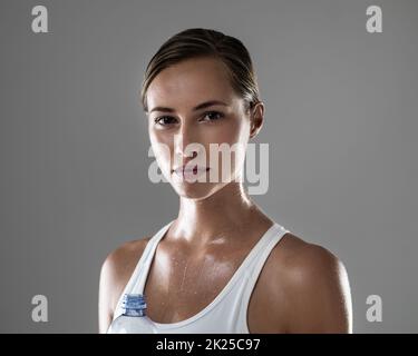 Je me sens bien et je le regarde. Portrait d'une brune confiante prenant une pause dans l'eau au cours de sa routine quotidienne d'exercice Banque D'Images