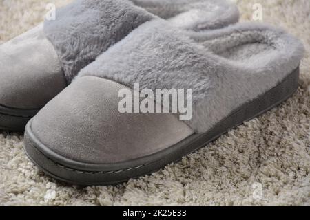 Une femme chaude chaussons sur tapis gris.Pantoufles confortables Banque D'Images