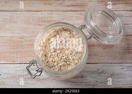 Flocons d'avoine non cuits dans un bol sur la table.Flocons d'avoine décortiqués et décortiqués, roulés en gros flocons entiers.Flocons d'avoine porridge, utilisés dans les granola ou les muesli. Banque D'Images