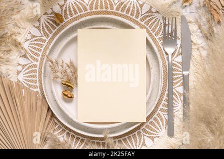 Table de mariage de boho avec carte vierge sur l'assiette près de l'herbe de pampas Banque D'Images