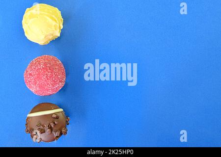 Bonbons au chocolat ou pralines sur fond bleu. Assortiment de pralines au chocolat sur fond bleu foncé avec espace de copie. Plan d'agencement, vue de dessus Banque D'Images