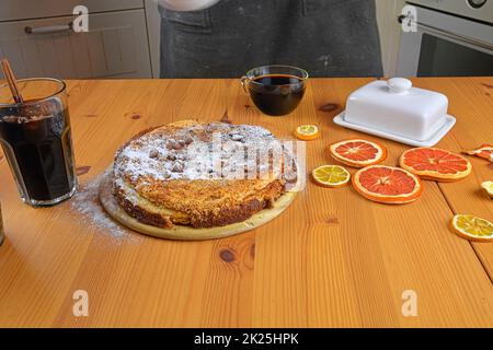 Gros plan d'un jeune homme du caucase saupoudrant du sucre sur un gâteau. Placé sur une table rustique en bois Banque D'Images