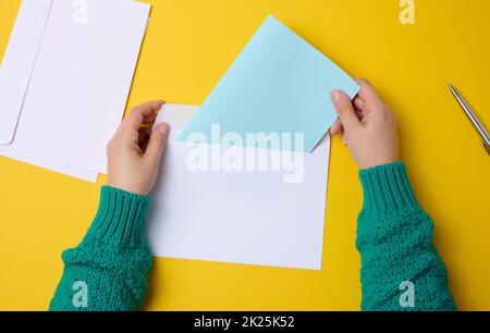 main femelle pour les enveloppes en papier blanc sur fond orange, vue de dessus.Envoi et réception de correspondance Banque D'Images