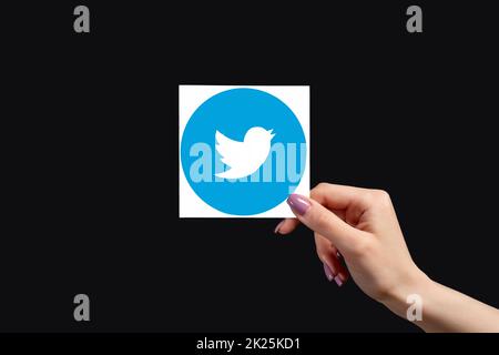 Kharkiv, Ukraine - June 05, 2020: Twitter logo. Global communication. Social media. Female hand holding microblogging app icon isolated on black copy Stock Photo