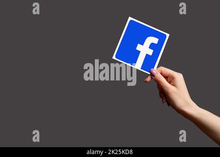 Kharkiv, Ukraine - June 05, 2020: Facebook icon. Digital marketing. Share social media. Woman hand showing application sign isolated on dark purple em Stock Photo