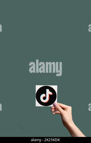 Kharkiv, Ukraine - June 05, 2020: TikTok icon. Social media. Online entertainment. Female hand showing music application sign isolated on dark teal co Stock Photo