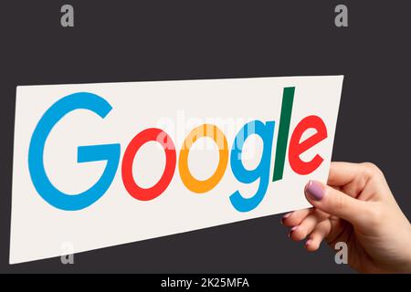 Kharkiv, Ukraine - June 05, 2020: Google logo. Software application. Global network. Female hand presenting colorful browser icon isolated on dark pur Stock Photo