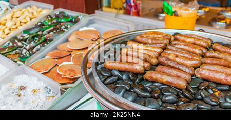 Saucisses grillées sur des pierres chaudes marché thaïlandais China Town Bangkok. Banque D'Images