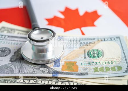 Stéthoscope noir avec billets en dollars américains sur fond de drapeau du Canada, concept des affaires et des finances. Banque D'Images