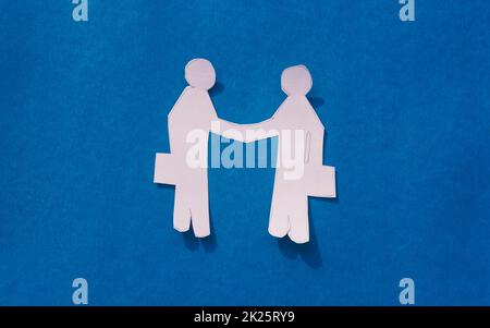 Deux hommes d'affaires se serrant la main sur fond bleu. Formes et figures décoratives de papuraft d'origami. Partenariat - concept d'opportunité d'affaire de travail d'équipe. Copier l'espace. Banque D'Images
