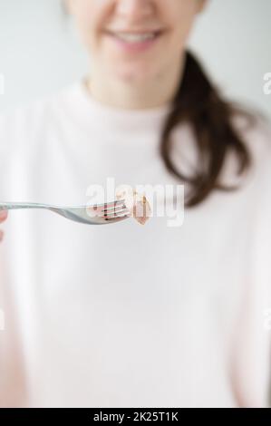 La fille tient un morceau de thon dans sa main sur une fourchette. Cuisine asiatique. Gros plan. Photo verticale. Banque D'Images