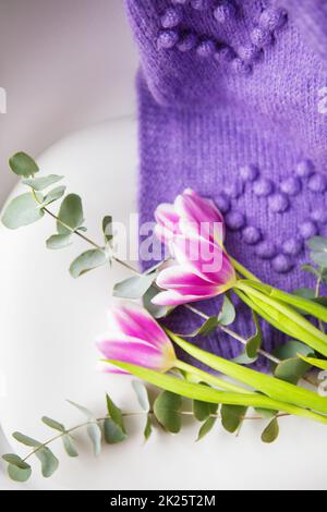 Printemps beau bouquet de tulipes pourpres avec eucalyptus sur une chaise blanche avec un chandail pourpre. Ambiance printanière, le 8 mars. Carte postale pour les vacances. Banque D'Images