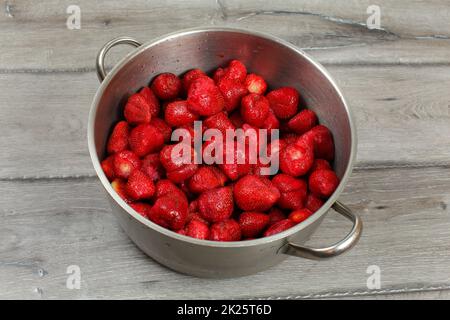 Marmite en acier inoxydable plein de fraises sur un bureau en bois. Préparation de la confiture de fraise faite maison. Banque D'Images