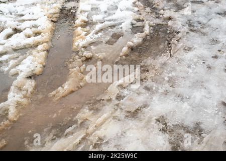 Route enneigée, pistes d'une voiture, temps orageux et glacé, temps d'hiver, rues glissantes, problème environnemental Banque D'Images