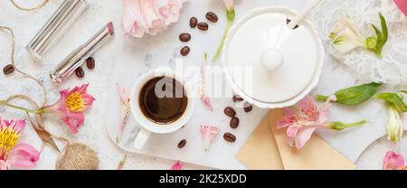 Tasse à café près des fleurs roses sur une table blanche Banque D'Images