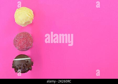 Bonbons au chocolat ou pralines sur fond rose.Assortiment de pralines au chocolat sur fond rose pastel avec espace de copie.Flat lay, vue de dessus Banque D'Images