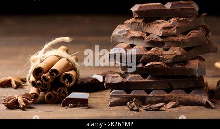 morceaux cassés de chocolat noir, bâtonnets de cannelle et anis étoilé sur une table en bois brun Banque D'Images