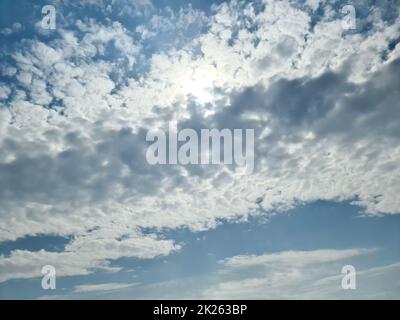 Belle vue sur les rayons du soleil avec quelques reflets de lentille et des nuages dans un ciel bleu Banque D'Images